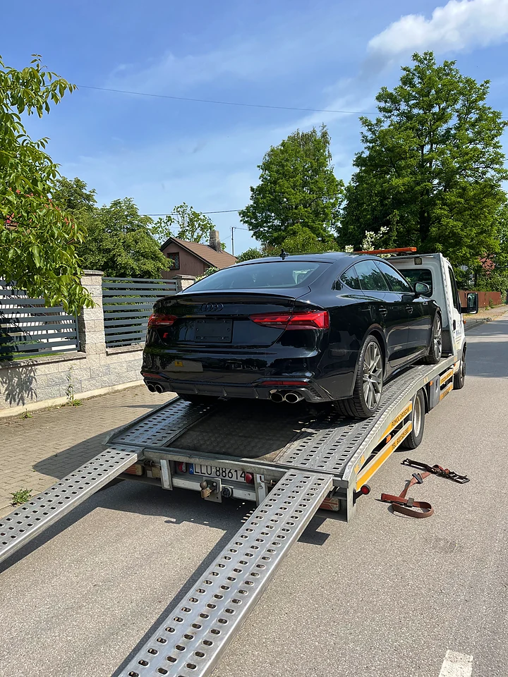 Black Audi S5 on a trailer outside a house